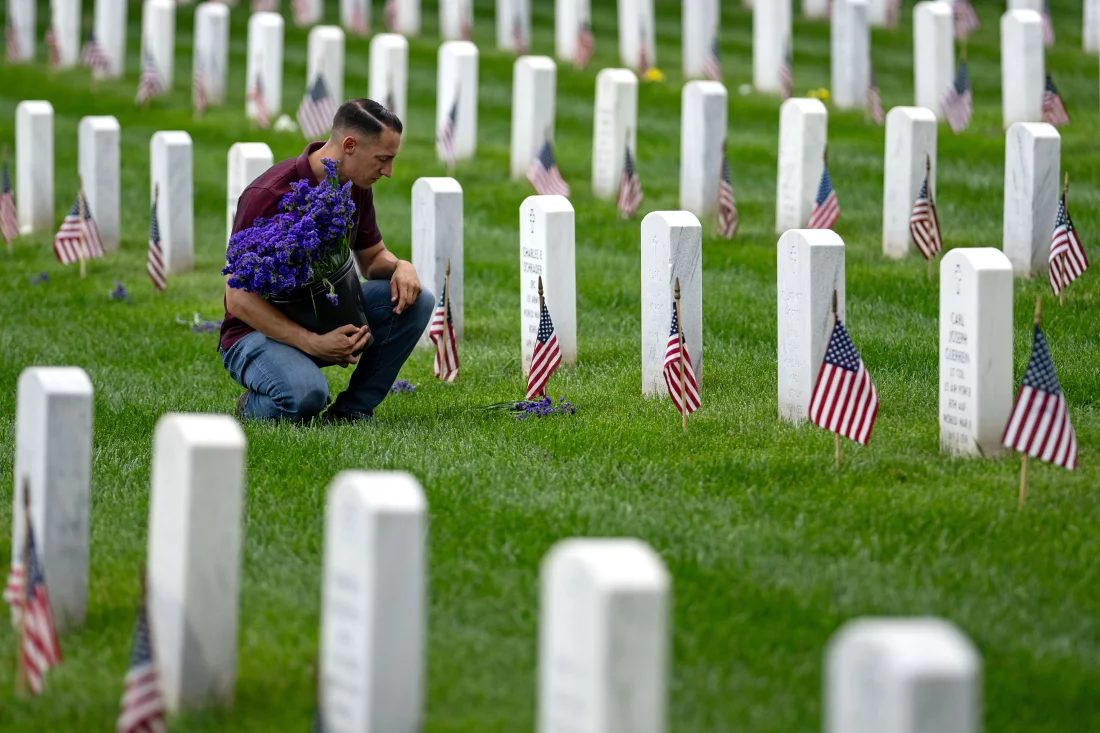 A man places flowers in front of headstones in Section 60, which mark the final resting place of service men and women at Arlington National Cemetery on May 27 in Arlington, Va. Kent Nishimura/Getty Images